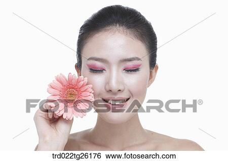 Stock Illustration - woman is closing her eyes holding blossom. Fotosearch
