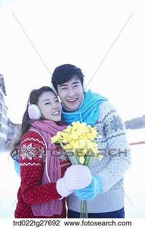 Stock Image - cordial couple holding flowers in same clothing. Fotosearch