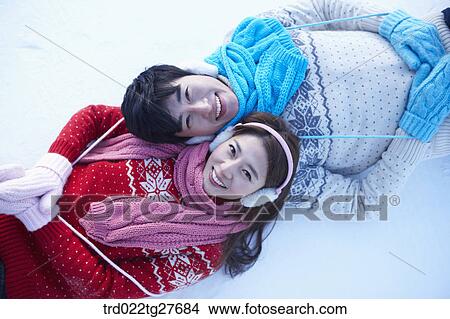 Picture - cordial couple lying down on snow. Fotosearch