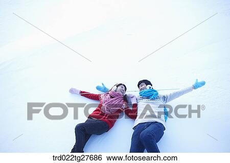 Stock Photograph - cordial couple lying down on snow. Fotosearch