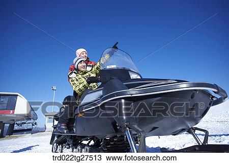 Stock Image - couple riding a motor ski vehicle. Fotosearch