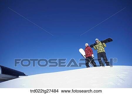 couple standing on the snow hill with a snow board View Large Photo Image Picture - couple standing on the snow hill with a snow board. Fotosearch