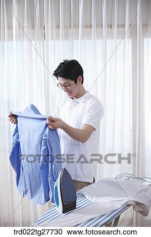 Stock Image - man ironing his shirt. Fotosearch