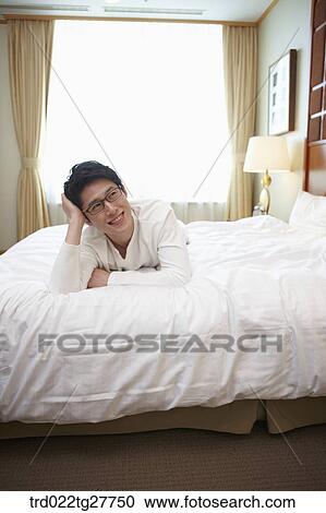 Stock Image - man lying down the bed. Fotosearch