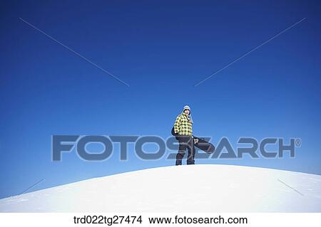 man standing on the snow hill with a snow board View Large Photo Image Picture - man standing on the snow hill with a snow board. Fotosearch