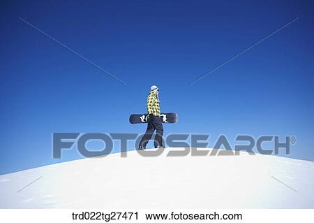 man standing on the snow hill with a snow board View Large Photo Image Stock Image - man standing on the snow hill with a snow board. Fotosearch