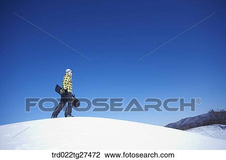 man standing on the snow hill with a snow board View Large Photo Image Stock Image - man standing on the snow hill with a snow board. Fotosearch