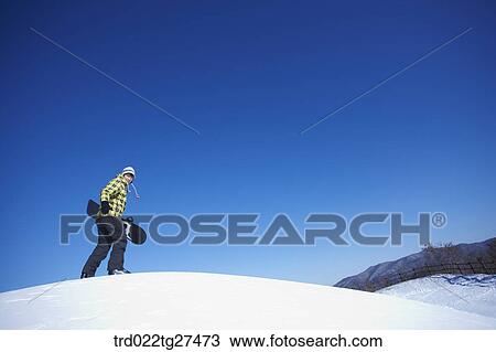man standing on the snow hill with a snow board View Large Photo Image Stock Image - man standing on the snow hill with a snow board. Fotosearch