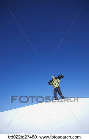 man standing on the snow hill with a snow board View Large Photo Image Stock Image - man standing on the snow hill with a snow board. Fotosearch
