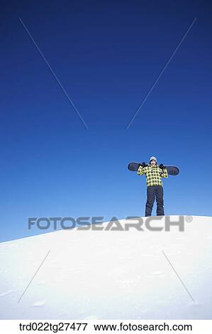 man standing on the snow hill with a snow board View Large Photo Image Stock Photo - man standing on the snow hill with a snow board. Fotosearch