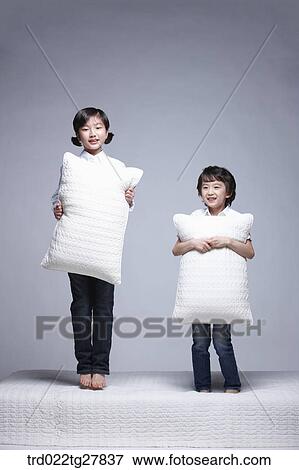 Stock Photo - children education boy and girl holding pillows on the bed. Fotosearch