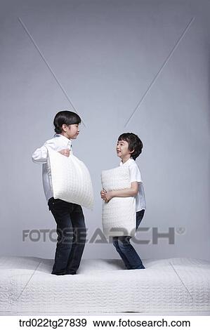Stock Photo - children education boy and girl holding pillows on the bed. Fotosearch