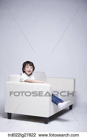 Stock Image - children education boy sitting on couch. Fotosearch