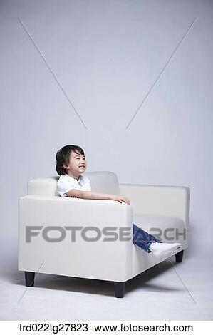 Stock Image - children education boy sitting on couch. Fotosearch