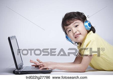 Stock Photograph - children education boy wearing headphone with laptop. Fotosearch