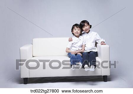 Stock Image - children education sitting on sofa together. Fotosearch