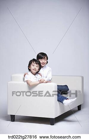 Stock Photograph - children education sitting on sofa together. Fotosearch