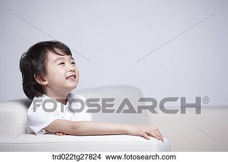 Picture - children educationboy sitting on couch with smile. Fotosearch