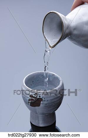 Stock Image - pour sake into glass. Fotosearch
