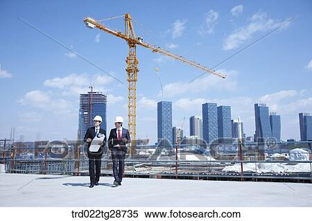 Stock Photography - business people walking at construction site. Fotosearch