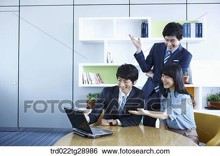 Stock Photograph - business people working together seeing laptop. Fotosearch