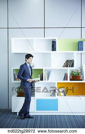 Stock Image - man holding book in office. Fotosearch