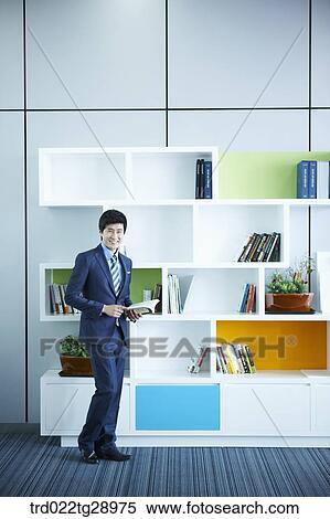 Stock Photography - man holding book in office. Fotosearch