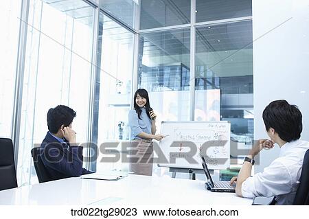 Stock Image - woman doing presentation to people in meeting room. Fotosearch