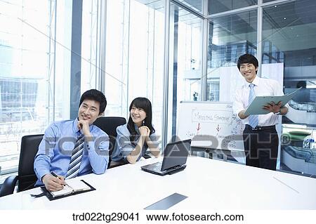 Stock Image - woman doing presentation to people in meeting room. Fotosearch