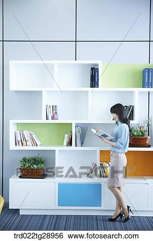 woman reads book by the bookshelf View Large Photo Image Stock Photograph - woman reads book by the bookshelf. Fotosearch