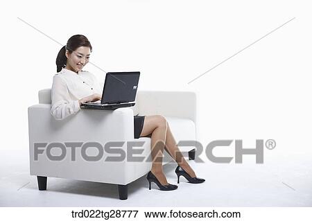 Stock Photo - woman using laptop on the sofa. Fotosearch