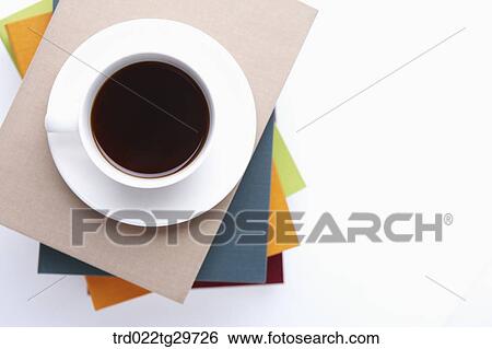 Stock Photograph - coffee cup on piled books. Fotosearch