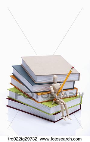 figurine sitting on the books holding pencil View Large Photo Image Stock Image - figurine sitting on the books holding pencil. Fotosearch