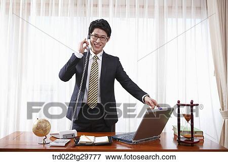 man answering the phone on the desk View Large Photo Image Stock Photo - man answering the phone on the desk. Fotosearch