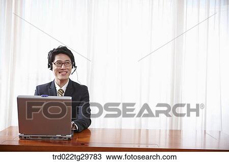 Stock Image - man doing his work using laptop. Fotosearch