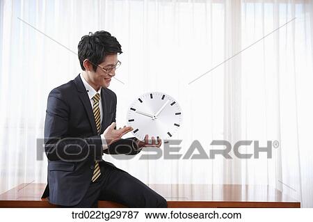 Stock Photo - man holding clock. Fotosearch