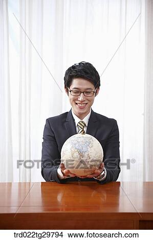Picture - man holding globe. Fotosearch