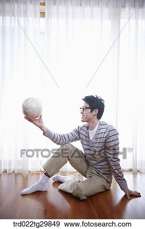 man holding globe sitting on floor View Large Photo Image Stock Photo - man holding globe sitting on floor. Fotosearch