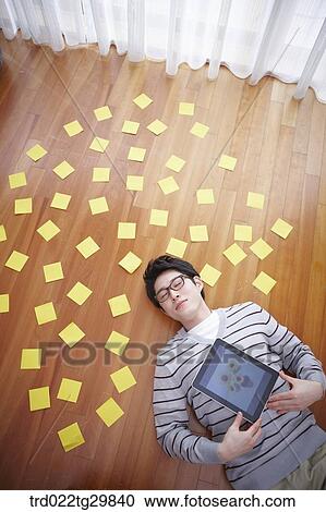 man holding tablet pc lying on the floor View Large Photo Image Stock Image - man holding tablet pc lying on the floor. Fotosearch