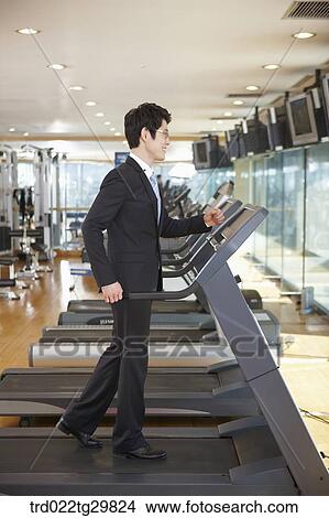 Picture - man is running on the machine. Fotosearch