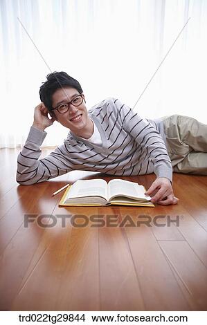 man lying on his side and reading the book on the floor View Large Photo Image Picture - man lying on his side and reading the book on the floor. Fotosearch