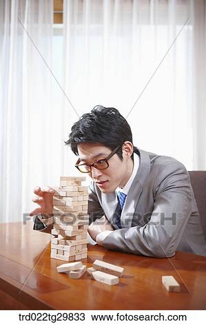 Stock Image - man picks the wooden block. Fotosearch