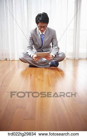 Picture - man seeing the tablet pc on the floor. Fotosearch