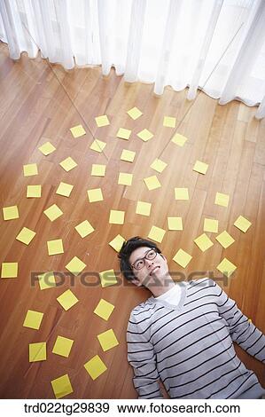 Stock Photo - man stretched his arms out lying on the floor. Fotosearch
