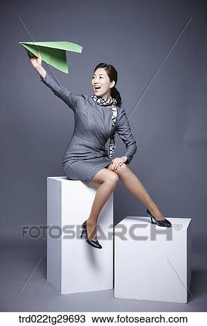 Stock Image - woman flying paper airplane. Fotosearch