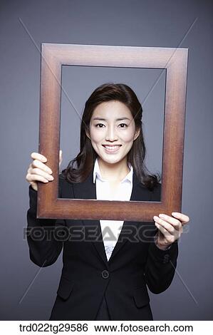 Stock Photograph - woman holding picture frame. Fotosearch