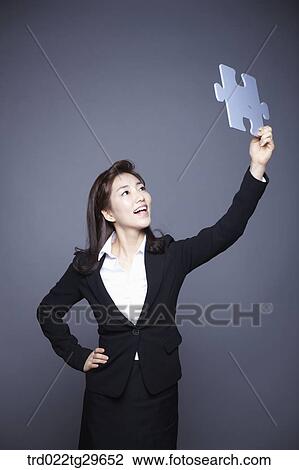Stock Image - woman holding puzzle piece. Fotosearch