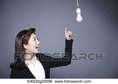 Stock Photograph - woman point at light bulb. Fotosearch