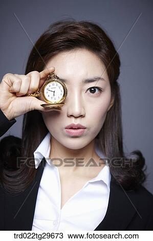 Stock Image - woman put a watch to her eye. Fotosearch