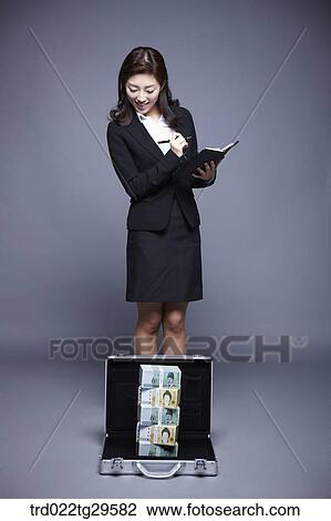 Stock Image - woman smiling seeing stack of money. Fotosearch